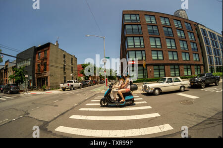 Les femmes voyagent sur un cyclomoteur électrique à partir de l'entreprise partage de cyclomoteurs Revel dans le quartier de Gowanus Brooklyn à New York le dimanche, Juin 23, 2019. Revel Transit a récemment annoncé une expansion de leur flotte d'un modeste 68 à 1000 cyclomoteurs étendre plus loin dans Brooklyn et Queens. (© Richard B. Levine) Banque D'Images