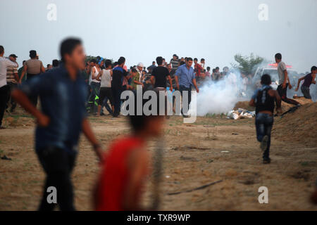 Un manifestant palestinien tente de ramasse une bombe lacrymogène pour le jeter de manifestants lors d'affrontements près de la frontière entre Israël et Gaza au sud de la bande de Gaza à l'est de Khan Yunis le 16 octobre 2015. Les Palestiniens ont appelé à une "révolution" de vendredi contre Israël en Cisjordanie, Gaza et Jérusalem, que les Juifs se sont armés avec des fusils pour balai, ébranlé par une vague d'attentats palestiniens qui ont secoué le pays. Photo par Ismael Mohamad/UPI Banque D'Images