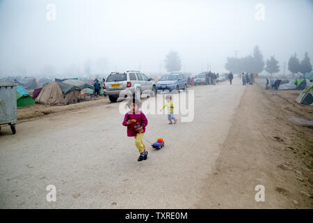 Une paire de jeunes enfants migrants sont vu jouant le long d'un chemin de terre dans un camp de réfugiés en Grèce. Les mères, les enfants et les familles sont parmi les 12 000 réfugiés bloqués dans un camp de fortune en Idomeni, Grèce, le long de la frontière avec la Macédoine en avril 2016 après la fermeture de la frontière. Photo de David Caprara/UPI Banque D'Images