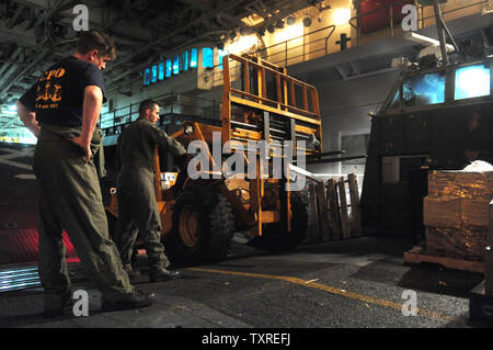 Personnel de la marine l'exploitation d'un chariot élévateur à fourche comme ils se déplacent sur un Landing Craft Air Cushion (LCAC) véhicule de la plate-forme humide de l'USS Bataan, en cours dans l'Océan Atlantique le 15 janvier 2010. L'USS Bataan est en cours en Haïti pour aider à l'effort de secours aux États-Unis après le tremblement de terre de magnitude 7 qui a dévasté le pays. UPI/Kevin Dietsch Banque D'Images