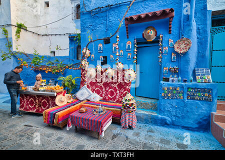 Chefchaouen, Maroc - 1 mai 2019 : vieil homme marocain vente de jus de fruits et de l'artisanat à la porte de sa maison Banque D'Images
