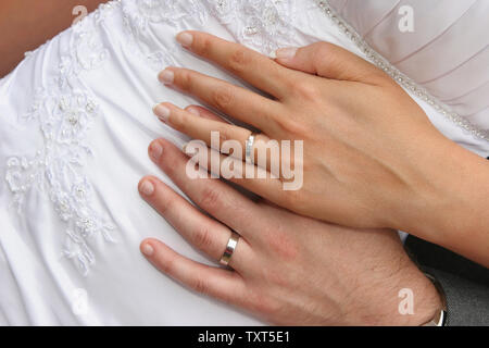 Jeunes mariés joindre les mains sur la taille de la mariée afficher les anneaux de mariage Banque D'Images