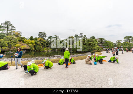 Kyoto, Japon - 17 Avril 2019 : Les gens travailleurs bénévoles séparer le blanc et le noir par du gravier green Spring garden à Imperial Palace avec étang Lake Banque D'Images