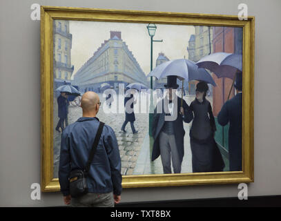 Le visiteur avant de la peinture 'Rue de Paris. Jour de pluie' par le peintre impressionniste Gustave Caillebotte (1877) affichée à son exposition à la Alte Nationalgalerie (ancienne Galerie Nationale) à Berlin, Allemagne. Banque D'Images