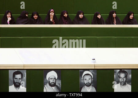 Les femmes iraniennes qui visitent le Parlement s'asseoir au-dessus des photos de martyrs lors d'un débat du Parlement européen sur trois autres Cabinet ministrers proposé par le Président Mahmoud Ahmadinejad, le 15 novembre 2009, à Téhéran, en Iran. Maryam Rahmanian/UPI Banque D'Images