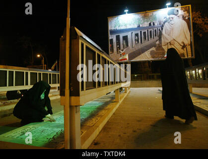 L'Iran comme nouvelle année commence une femme iranienne prie en face d'une grande image de l'Iran, l'Ayatollah Ali Khamneie près de cimetière des martyrs pour tous ceux qui ont été tués pendant la guerre Iran-Irak (1980-1988) qu'une autre femme arrive à prier à Qazvin, 83 milles (150 Km) de Téhéran le 21 mars 2007. UPI (photo) Banque D'Images