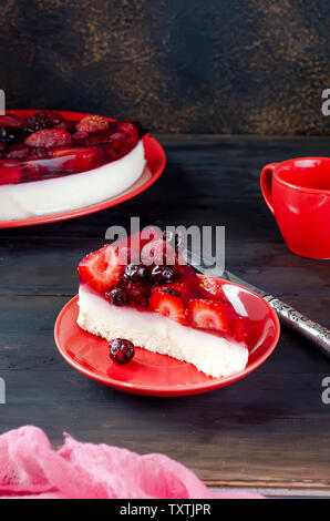 Gâteau mousse à la crème de fruits avec la gelée et les baies fraîches sur la table rustique foncé de délicieux petits fruits rouges frais. La confiture. La vaseline. Le gâteau au fromage. Banque D'Images