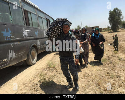 Un membre des forces de sécurité irakiennes porte un sac comme il aide les civils, qui ont fui leurs maisons dans et autour de Fallouja en raison des combats entre les forces du gouvernement iraquien et de l'État islamique (EST), au sud de Fallujah, Iraq, 8 juin 2016. photo par Abbas Mohammed /UPI Banque D'Images