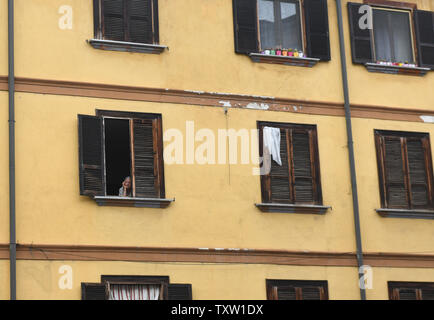 Vieille dame scrutant de fenêtre appartement en Italie, Europe Banque D'Images
