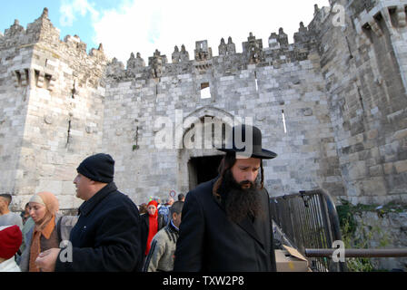 Un ultra-orthodoxe juif promenades par des Palestiniens à l'extérieur de la Porte de Damas à Jérusalem, 2 janvier 2007. L'ancien maire de Jérusalem, Teddy Kollek est décédé aujourd'hui à l'âge de 95. Il était le maire de Jérusalem pendant 28 ans et était connu pour la coexistence entre Juifs et Arabes et la construction de Jérusalem moderne. (Photo d'UPI/Debbie Hilll) Banque D'Images