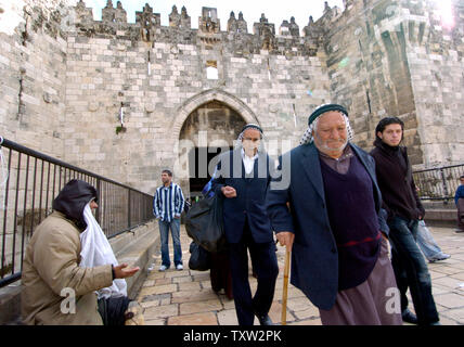 Les palestiniens à pied par un mendiant à l'extérieur de la Porte de Damas à Jérusalem, 2 janvier 2007. L'ancien maire de Jérusalem, Teddy Kollek est décédé aujourd'hui à l'âge de 95. Il était le maire de Jérusalem pendant 28 ans et était connu pour la coexistence entre Juifs et Arabes et la construction de Jérusalem moderne. (Photo d'UPI/Debbie Hilll) Banque D'Images