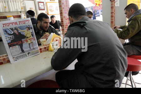 La police des frontières israélienne manger le petit déjeuner dans une boulangerie de Jérusalem avec un journal israélien doté d''une photo de couverture du Président des Etats-Unis Barack Obama et son épouse Michelle le jour de l'investiture, le 21 janvier 2009. L'hébreu, sous le titre 'Good Morning America'. (Photo d'UPI/Debbie Hill) Banque D'Images