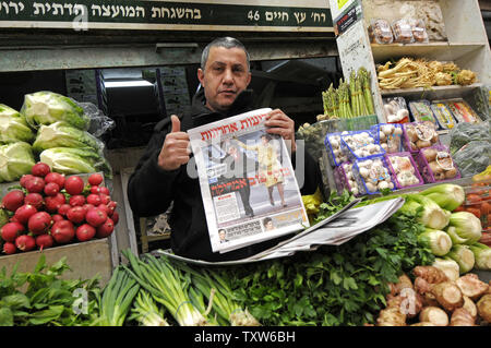 Un vendeur de légumes israélienne à Jérusalem donne un o.k. signer tout en tenant un journal israélien avec une photo de couverture du Président des Etats-Unis Barack Obama et son épouse Michelle le jour de l'investiture, le 21 janvier 2009. L'hébreu, sous le titre 'Good Morning America'. (Photo d'UPI/Debbie Hill) Banque D'Images