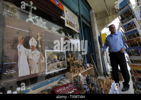 Un vendeur de Palestiniens à Bethléem, en Cisjordanie, se tient près d'une affiche du Pape Benoît XVI qui effectuera la messe papale en place de la Nativité à Bethléem, la semaine prochaine, le 8 mai 2009. Les musulmans représentent deux tiers de la population de Bethléem, le berceau du christianisme, où la tradition croit que Jésus est né.(Photo UPI/Debbie Hill) Banque D'Images