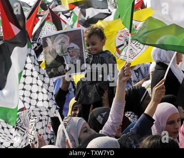 Un garçon palestinien sourit à côté d'un poster de Yasser Arafat lors d'un rassemblement marquant le cinquième anniversaire de la fin leader palestinien la mort de Yasser Arafat à Ramallah, en Cisjordanie, le 11 novembre 2009. Arafat est mort à 75 ans, dans un hôpital parisien le 11 novembre 2004. UPI/Debbie Hill Banque D'Images