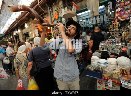 Un homme saute d'un shofar, une corne de bélier, à l'extérieur d'une boutique dans le marché Mahane Yehuda à Jérusalem, un jour avant le début de Roch hachana, le Nouvel An juif, le 7 septembre 2010. Rosh HaShanah commence au coucher du soleil mercredi et depuis deux jours. Le Premier ministre israélien Benjamin Netanyahu a déclaré dans son adresse de Roch Hachana que tout accord de paix avec les Palestiniens sera basé sur la sécurité d'Israël et la reconnaissance d'Israël comme État juif. UPI/Debbie Hill Banque D'Images