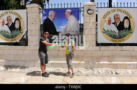 Les touristes se tenir en face d'une bannière du président palestinien Mahmoud Abbas et le Pape François, qui dit, 'Bienvenue à l'Etat de Palestine", en dehors de l'église de la Nativité, où la tradition croit que Jésus Christ est né, à Bethléem, en Cisjordanie, le 22 mai 2014. Pape Francis tiendra une place de la Crèche en masse à l'extérieur de l'église de la nativité Le 25 mai, trois jours de son pèlerinage en Terre Sainte. UPI/Debbie Hill Banque D'Images