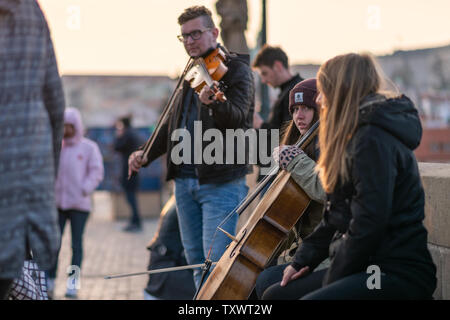 PRAGUE, RÉPUBLIQUE TCHÈQUE - 10 AVRIL 2019 : un musicien femelle et son groupe jouer aux touristes sur le pont Charles à Prague lors d'un coucher du soleil faible. Banque D'Images