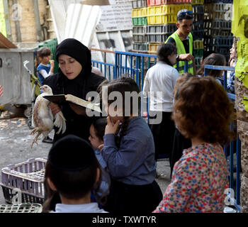 Une femme juive ultra-orthodoxes prie tout en tenant un poulet tout en exécutant la cérémonie des 'Kapparot À Mea Shearim à Jérusalem, Israël, le 10 octobre 2016. Le rituel juif transferts symboliquement les péchés de l'année dernière pour le poulet et s'effectue avant Yom Kippour, le Jour du Grand Pardon, le jour le plus saint du calendrier juif. Yom Kippour commence au coucher du soleil le 11 octobre cette année. Photo par Debbie Hill/UPI Banque D'Images