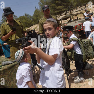 Un garçon juif détient une arme d'assaut sur le 70e jour de l'indépendance d'Israël à un affichage militaire dans le Ma'ale Adumim colonie juive en Cisjordanie, le 19 avril 2018. Photo par Debbie Hill/UPI Banque D'Images