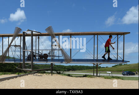 Un jeune joue sur la sculpture intitulée "December 17, 1903' comme il se reproduit la scène du premier vol de l'Wright Brothers le Wright Brothers National Memorial de Kill Devil Hills, près de Kitty Hawk sur les Outer Banks de la Caroline du Nord le 25 juillet 2015. La sculpture représentant un poids de 10 000 livres à bord d'Orville, tandis que l'avion des frères Wright Flyer '1' pesait 605 livres. Le plan original est au Smithsonian à Washington, DC. Orville et Wilbur Wright ont fait leurs essais de planeur de 1900 et a volé le premier avion sur cette plage de sable fin le 17 décembre 1903. L Banque D'Images