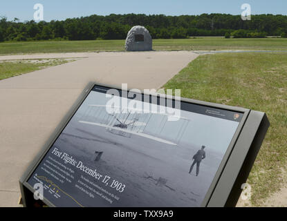 Une peste montrant l'historique photo de John Daniels est affiché près de le piquage marker (haut, centre) pour les premiers vols des frères Wright à l'Wright Brothers National Memorial de Kill Devil Hills, près de Kitty Hawk sur les Outer Banks de la Caroline du Nord le 25 juillet 2015. Orville et Wilbur Wright ont fait leurs essais de planeur de 1900 et a volé le premier avion sur cette plage de sable fin le 17 décembre 1903. Le premier vol ce jour parcouru 120 pieds et a duré 12 secondes, le quatrième a 852 pieds et a duré 59 secondes. Photo de Pat Benic/UPI Banque D'Images