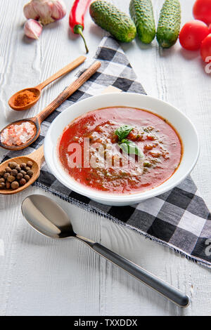 Soupe de tomate au basilic, poivre, ail et concombre sur fond de bois. Soupe gaspacho espagnol. Banque D'Images