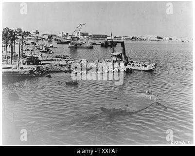 Campagne de bombardement. Europe & Afrique du Nord ; la portée et contenu : Tripoli, Libye, Afrique du Nord. Partie de la bombe-blasted waterfront à Tripoli. L'épave d'un remorqueur se trouve à côté d'un cratère fait par une bombe alliée. Au premier plan on peut voir le hulk submergée d'une barge d'alimentation. Banque D'Images