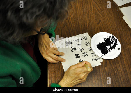 La calligraphie. Une femme utilise le pinceau et l'encre pour tracer les caractères chinois traditionnels Banque D'Images