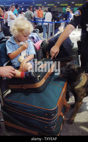 Agent de police de l'aéroport de Los Angeles Michael Manahan guide son chien, Baso, pour vérifier l'assurance en tant que voyageurs à attendre en ligne à l'Aéroport International de Los Angeles le 11 août 2006. Les gouverneurs de Californie, New York et du Massachusetts envoyé les troupes de la Garde nationale pour renforcer la sécurité dans les aéroports après autorités britanniques ont arrêté 24 personnes dans un prétendu complot visant à faire exploser des avions à destination des États-Unis à l'aide d'explosifs liquides communs déguisé en. (Photo d'UPI/Jim Ruymen) Banque D'Images