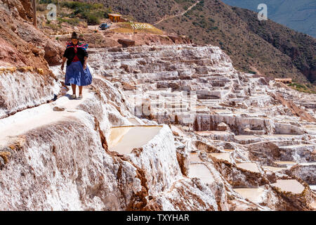 Femme marche sur péruvienne Salineras de Maras Maras / Mines de sel. L'extraction de sel dans les salines de Maras, terrasses et bassins, le Pérou La Vallée Sacrée. Banque D'Images