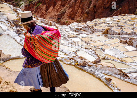 Femme marche sur péruvienne Salineras de Maras Maras / Mines de sel. L'extraction de sel dans les salines de Maras, terrasses et bassins, le Pérou La Vallée Sacrée. Banque D'Images