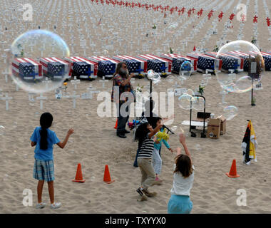 Les jeunes s'amusent comme ils chase près de bulles, recouvert du drapeau d'écrins sur l'affichage à l'ouest d'Arlington Memorial Project à Santa Monica, Californie le 26 mai 2007. La plage dispose de milliers de croisements memorial représentant les 3 452 soldats qui sont morts en Irak. (Photo d'UPI/Jim Ruymen) Banque D'Images