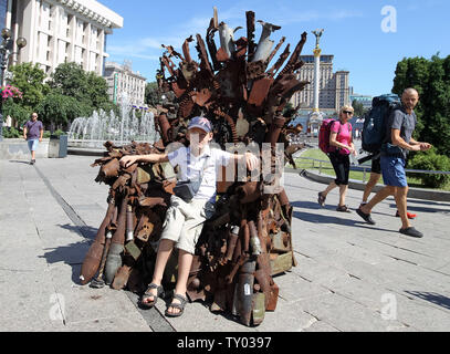 25 juin 2019 - Kiev, Ukraine - un petit garçon est assis sur le trône de fer le 'l'Est' d'art, qui a présenté sur la place de l'indépendance, à Kiev, Ukraine, le 25 juin 2019. "Le trône de fer de l'Est' a été créé un bénévole ukrainienne fighter Denis Bushtets dans la zone de conflit de la guerre dans l'Est de l'Ukraine près de Donetsk en 2016. L'objet d'art est faite à partir de l'épave de l'armure du réservoir, parties de démoli le matériel militaire, mitrailleuses, obus, cartouches et flacons du soldat et il n'est plus de 600 kg de poids. Un prototype d'un célèbre discours du Trône de fer Game of Thrones série TV est un rappel d'un mag Banque D'Images