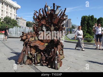 25 juin 2019 - Kiev, Ukraine - Les gens recherchent sur le "Trône de fer de l'Est' d'art, qui a présenté sur la place de l'indépendance, à Kiev, Ukraine, le 25 juin 2019. "Le trône de fer de l'Est' a été créé un bénévole ukrainienne fighter Denis Bushtets dans la zone de conflit de la guerre dans l'Est de l'Ukraine près de Donetsk en 2016. L'objet d'art est faite à partir de l'épave de l'armure du réservoir, parties de démoli le matériel militaire, mitrailleuses, obus, cartouches et flacons du soldat et il n'est plus de 600 kg de poids. Un prototype d'un célèbre discours du Trône de fer Game of Thrones série TV est un rappel d'une sanglante con Banque D'Images