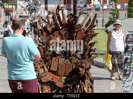 25 juin 2019 - Kiev, Ukraine - Les gens recherchent sur le "Trône de fer de l'Est' d'art, qui a présenté sur la place de l'indépendance, à Kiev, Ukraine, le 25 juin 2019. "Le trône de fer de l'Est' a été créé un bénévole ukrainienne fighter Denis Bushtets dans la zone de conflit de la guerre dans l'Est de l'Ukraine près de Donetsk en 2016. L'objet d'art est faite à partir de l'épave de l'armure du réservoir, parties de démoli le matériel militaire, mitrailleuses, obus, cartouches et flacons du soldat et il n'est plus de 600 kg de poids. Un prototype d'un célèbre discours du Trône de fer Game of Thrones série TV est un rappel d'une sanglante con Banque D'Images