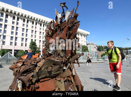 25 juin 2019 - Kiev, Ukraine - un garçon cherche sur le trône de fer le 'l'Est' d'art, qui a présenté sur la place de l'indépendance, à Kiev, Ukraine, le 25 juin 2019. "Le trône de fer de l'Est' a été créé un bénévole ukrainienne fighter Denis Bushtets dans la zone de conflit de la guerre dans l'Est de l'Ukraine près de Donetsk en 2016. L'objet d'art est faite à partir de l'épave de l'armure du réservoir, parties de démoli le matériel militaire, mitrailleuses, obus, cartouches et flacons du soldat et il n'est plus de 600 kg de poids. Un prototype d'un célèbre discours du Trône de fer Game of Thrones série TV est un rappel d'une sanglante con Banque D'Images