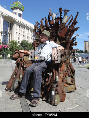 25 juin 2019 - Kiev, Ukraine - Un vieil homme est assis sur le trône de fer de l'Est' d'art, qui a présenté sur la place de l'indépendance, à Kiev, Ukraine, le 25 juin 2019. "Le trône de fer de l'Est' a été créé un bénévole ukrainienne fighter Denis Bushtets dans la zone de conflit de la guerre dans l'Est de l'Ukraine près de Donetsk en 2016. L'objet d'art est faite à partir de l'épave de l'armure du réservoir, parties de démoli le matériel militaire, mitrailleuses, obus, cartouches et flacons du soldat et il n'est plus de 600 kg de poids. Un prototype d'un célèbre discours du Trône de fer Game of Thrones série TV est un rappel d'une sanglante Banque D'Images