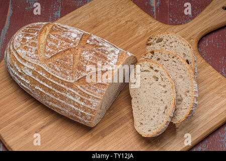 Miche de pain au levain avec des tranches sur planche de bois Banque D'Images