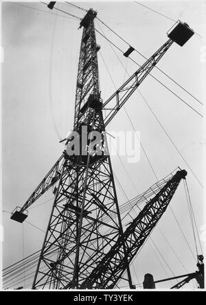 L'érection d'une tour à effectuer l'ensemble de courroie de convoyeur suspendu par câble à partir de la rivière gravel plant à la centrale. ; Portée et contenu : la photographie de deux volumes d'une série d'albums de photos documentant la construction du barrage de Grand Coulee et travaux connexes sur le bassin du Columbia Projet. Banque D'Images