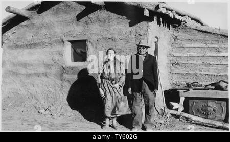 Couple indien debout devant l'enduisaient de boue log cabin Banque D'Images