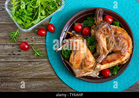Lapin cuit entier avec les verts et les tomates sur une assiette. Diététique savoureuse viande. Haut de la vue, télévision lay. Banque D'Images