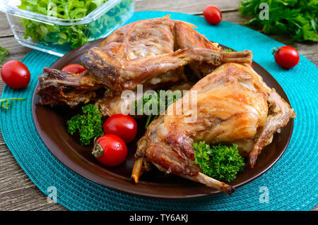 Lapin cuit entier avec les verts et les tomates sur une assiette. Diététique savoureuse viande. Banque D'Images