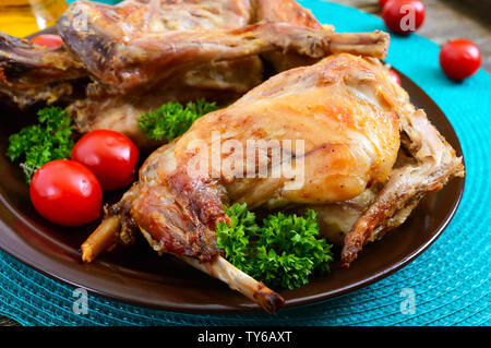 Lapin cuit entier avec les verts et les tomates sur une assiette. Diététique savoureuse viande. Banque D'Images