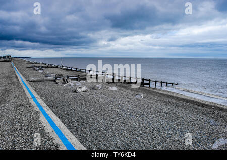 Une plage de galets dans le Suffolk et les brise-lames avec ciel nuageux Banque D'Images