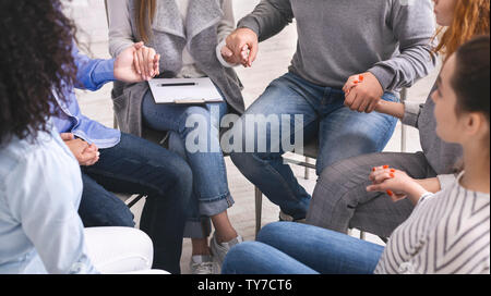 Groupe de toxicomanes tenant les mains, assis en cercle de confiance Banque D'Images