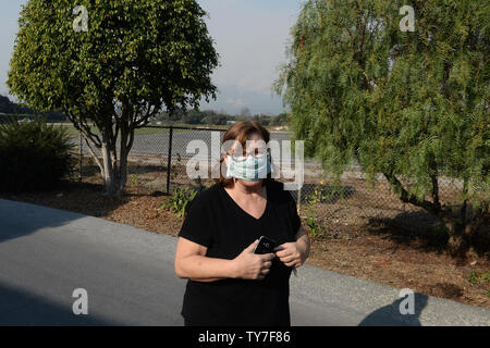 Un résident local met un masque respiratoire, alors qu'elle est sortie pour voir un feu de structure dans le début de soirée, juste après le coucher du soleil est à Carpinteria, en Californie le 11 décembre 2017. Thomas l'incendie, la plus grande de l'ensemble de feu flambe la Californie du Sud, est maintenant plus de 350 milles carrés -- et les pompiers luttent toujours pour l'obtenir sous contrôle, les autorités ont dit. Photo par Jim Ruymen/UPI Banque D'Images