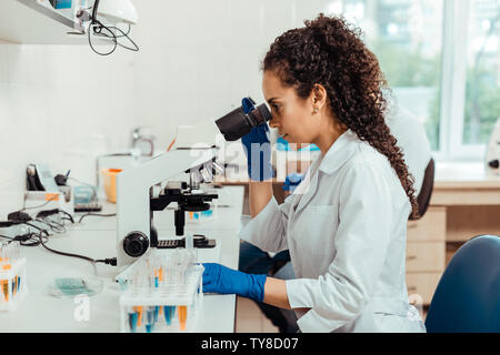 Jeune femme assise en face du microscope Banque D'Images