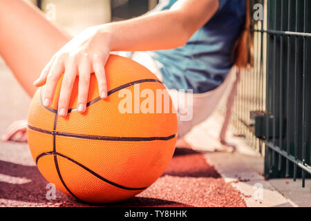 Petite fille aux petites mains holding orange balle de basket-ball Banque D'Images