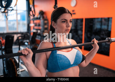 Dark-haired woman working out top court avec barbell Banque D'Images